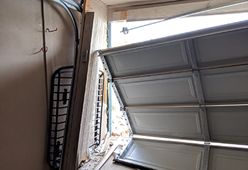 Severely damaged white garage door collapsed outward onto the driveway of a Winter Park home, showing extensive structural failure.