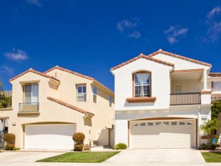 Two modern homes in Fern Park, FL, each featuring stylish, custom-designed garage doors and well-maintained exteriors under a clear blue sky.