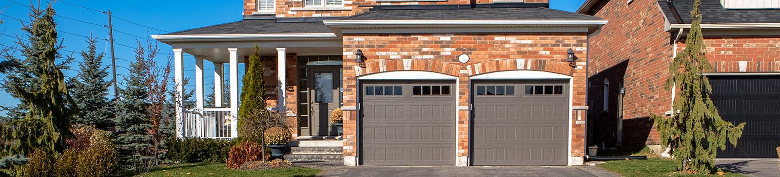 Front view of a brick home in Fern Park, FL with two modern brown garage doors, landscaped yard, and a welcoming entryway.