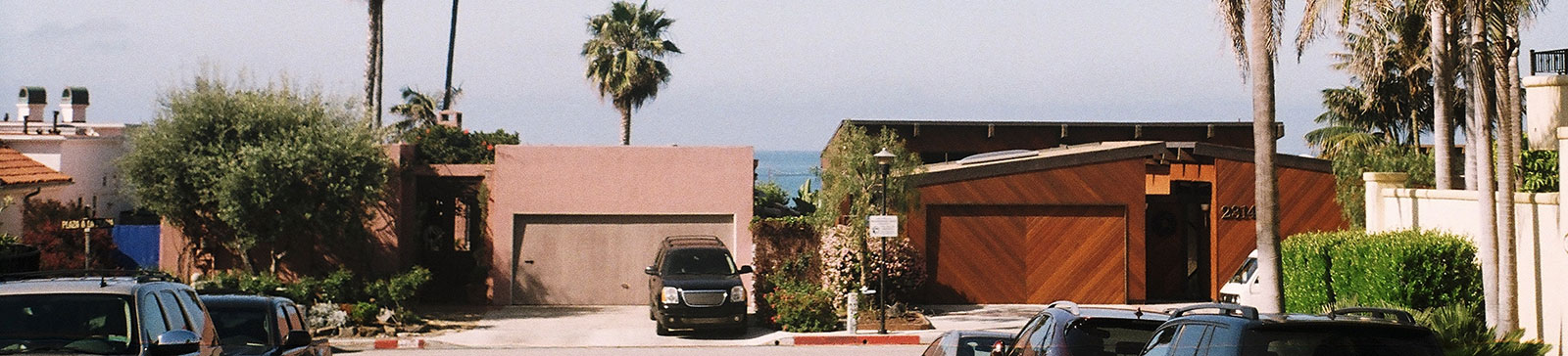 View of a residential neighborhood in Fern Park, FL with modern garage doors and palm trees, representing garage door repair and home improvement.