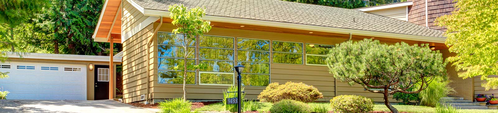 Contemporary Fern Park home with a white garage door and large windows, surrounded by lush landscaping and trees.