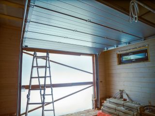 Professional Garage Door Installation – Fern Park FL Interior view of a garage during a new door installation in Fern Park, FL, featuring a partially installed sectional door, ladder, and construction materials.